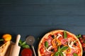 Delicious pizza and ingredients on wooden background