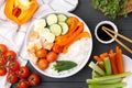 Delicious poke bowl and ingredients on black wooden table, flat lay