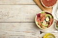 Delicious pomelo salad with prosciutto in half of fruit on white wooden table, flat lay. Space for text Royalty Free Stock Photo