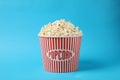 Delicious popcorn in paper bucket on light blue