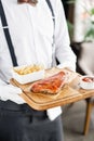 The waiter is holding a wooden plate Delicious Pork ribs. Full rack of ribs BBQ on wooden plate with french fries and Royalty Free Stock Photo
