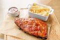 Delicious Pork ribs. Full rack of ribs BBQ on wooden plate with french fries and salad Royalty Free Stock Photo