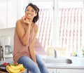 This is delicious. Portrait of a young woman enjoying an apple while sitting on a kitchen counter.