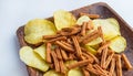 Delicious potato chips and salted rye bread crackers on a dark wooden plate, on a white background. high-calorie snack Royalty Free Stock Photo