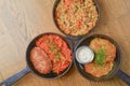 Delicious potato pancakes with sour cream, rice with meat and vegetables and Chicken Kiev cutlet served in frying pans. Royalty Free Stock Photo