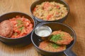 Delicious potato pancakes with sour cream, rice with meat and vegetables and Chicken Kiev cutlet served in frying pans. Royalty Free Stock Photo