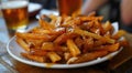 Delicious poutine on a plate with a pint of beer in the background