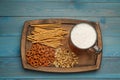 Delicious pretzel crackers, salted sticks, peanuts and mug of beer on light blue wooden table, top view Royalty Free Stock Photo