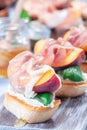 Delicious prosciutto peach bruschetta. Crostini, cream cheese, basil, peach and prosciutto, closeup