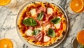 Delicious prosciutto pizza with mozzarella and basil, served with refreshing orange drinks on marble table Royalty Free Stock Photo