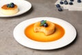 Delicious puddings with caramel and blueberries on grey table Royalty Free Stock Photo