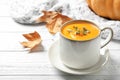 Delicious pumpkin soup in cup on wooden table Royalty Free Stock Photo