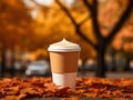 Delicious pumpkin spice latte cappuccino in a to go paper cup standing on a bench in autumn park