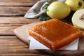 Delicious quince paste on wooden table, closeup. Space for text