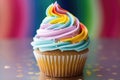 Delicious rainbow colored cupcake decorated with frosting and candy drops