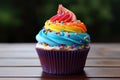 Delicious rainbow colored cupcake decorated with frosting and candy drops Royalty Free Stock Photo