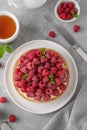 Delicious raspberry tart with vanilla custard cream sprinkled with powdered sugar on a white plate on a gray concrete background. Royalty Free Stock Photo