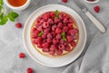 Delicious raspberry tart with vanilla custard cream sprinkled with powdered sugar on a white plate on a gray concrete background. Royalty Free Stock Photo