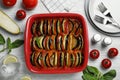 Delicious ratatouille in baking dish and ingredients on white wooden table, flat lay Royalty Free Stock Photo