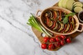 Delicious ratatouille and ingredients on white marble table, top view. Space for text Royalty Free Stock Photo