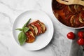 Delicious ratatouille served with basil on white marble table, flat lay