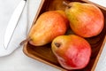 Delicious red pears in wooden bowl, napkin and knife. Royalty Free Stock Photo