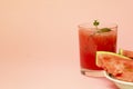 Delicious red watermelon juice with sliced fruit pieces on a plate. A sprig of mint in a glass. Copy space. Summer food concept Royalty Free Stock Photo