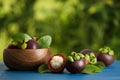 Delicious ripe mangosteen fruits on blue wooden table outdoors, space for text