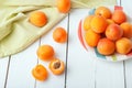 Delicious ripe organic orange apricots in a beautiful plate decorated with green napkin laying on white wooden table.