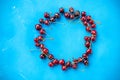 Delicious ripe red cherries on the blue background arranged in circle frame.Creative layout with fresh ripe berries