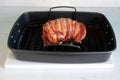 Delicious roast turkey crown wrapped with bacon in a black baking tray