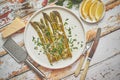 Delicious roasted asparagus served on white ceramic plate. With parmesan cheese, parsley and lemon.