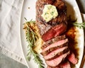 Delicious roasted beef tenderloin with herb butter on white plate garnished with fresh rosemary. Holiday meal for family dinner