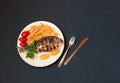 Delicious roasted dorado  fish with lemon, fried potatoes, fresh parsley and tomatoes on white plate on dark background. Royalty Free Stock Photo