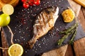 Delicious roasted dorado or Gilt-head bream fish with lemon and orange slices, spices, and fresh rosemary on baking sheet, close- Royalty Free Stock Photo