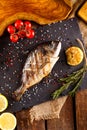 Delicious roasted dorado or Gilt-head bream fish with lemon and orange slices, spices, and fresh rosemary on baking sheet, close- Royalty Free Stock Photo