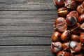 Delicious roasted edible chestnuts on black wooden table, flat lay. Space for text Royalty Free Stock Photo