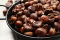 Delicious roasted edible chestnuts in frying pan on table, closeup Royalty Free Stock Photo