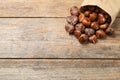 Delicious roasted edible chestnuts in paper bag on wooden table. Space for text Royalty Free Stock Photo