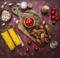 Delicious roasted lamb ribs with hot sauce and herbs on a cutting board with corn and vegetables wooden rustic background top v