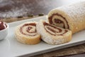 Delicious roll cake with guava cream jelly and sugar sliced on white platter and blurred background