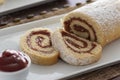 Delicious roll cake with guava cream jelly and sugar sliced on white platter and blurred background