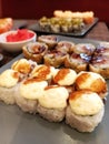 Close-up of delicious rolls baked under a cheese cap next to fried rolls on a platter and with ginger on a restaurant table Royalty Free Stock Photo