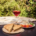 Delicious rustic crispy pie with meat and herbs. Served on wooden plate, surrounded by glass of red wine, white sauce and ve Royalty Free Stock Photo