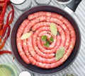 Delicious rustic raw meat sausages in frying pan, with bay leaves and fresh herbs in the kitchen. Royalty Free Stock Photo