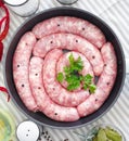 Delicious rustic raw meat sausages in frying pan, with bay leaves and fresh herbs in the kitchen. Royalty Free Stock Photo