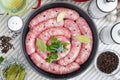 Delicious rustic raw meat sausages in frying pan, with bay leaves and fresh herbs in the kitchen. Royalty Free Stock Photo