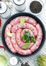 Delicious rustic raw meat sausages in frying pan, with bay leaves and fresh herbs in the kitchen. Royalty Free Stock Photo