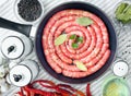 Delicious rustic raw meat sausages in frying pan, with bay leaves and fresh herbs in the kitchen. Royalty Free Stock Photo