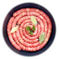Delicious rustic raw meat sausages in frying pan, with bay leaves and fresh herbs in the kitchen Royalty Free Stock Photo